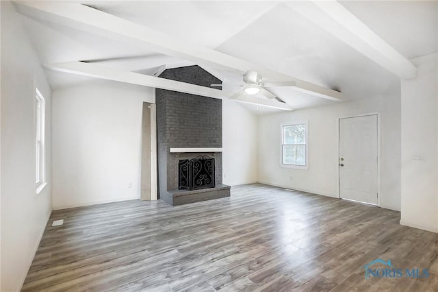 unfurnished living room with ceiling fan, a fireplace, hardwood / wood-style flooring, and lofted ceiling with beams