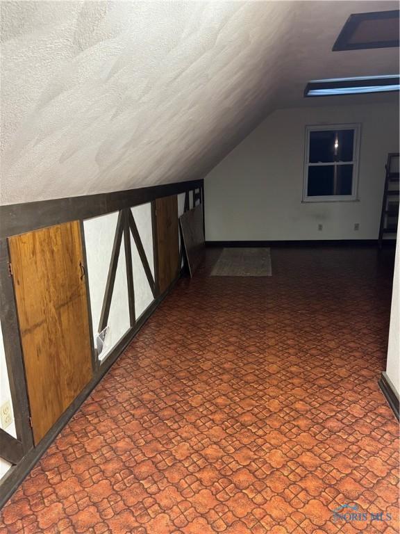 additional living space with lofted ceiling and a textured ceiling