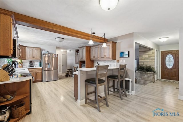 kitchen with kitchen peninsula, backsplash, appliances with stainless steel finishes, and decorative light fixtures