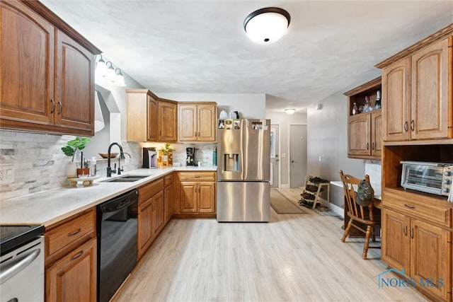 kitchen featuring tasteful backsplash, appliances with stainless steel finishes, sink, and light hardwood / wood-style flooring