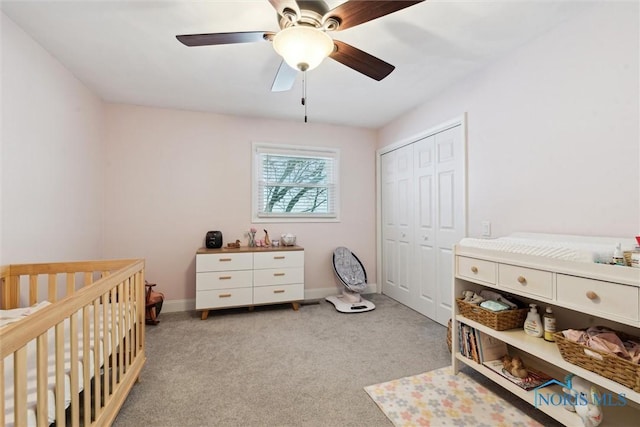 bedroom with ceiling fan, light colored carpet, a closet, and a crib