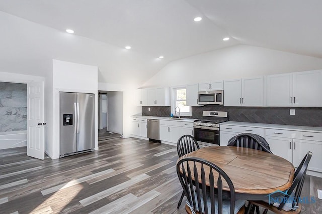 kitchen with lofted ceiling, sink, dark wood-type flooring, appliances with stainless steel finishes, and white cabinets