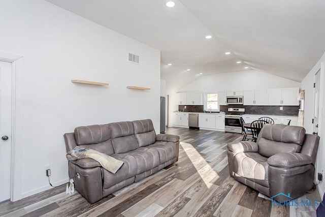 living room with sink, vaulted ceiling, and wood-type flooring