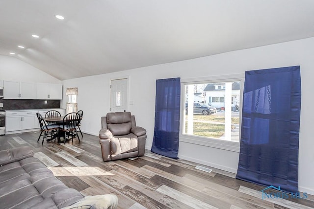 living room featuring lofted ceiling and light hardwood / wood-style flooring