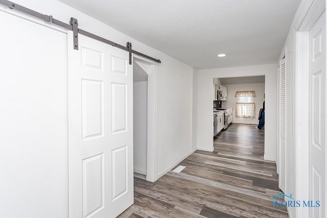 corridor featuring a barn door and dark hardwood / wood-style flooring