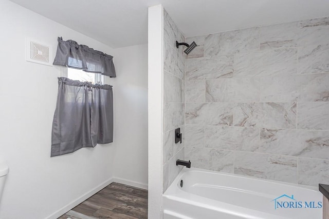 full bathroom featuring tiled shower / bath, vanity, toilet, and hardwood / wood-style floors