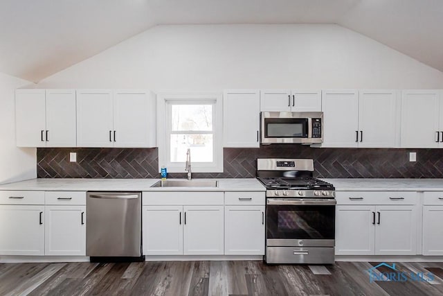 kitchen with lofted ceiling, stainless steel appliances, sink, and white cabinets