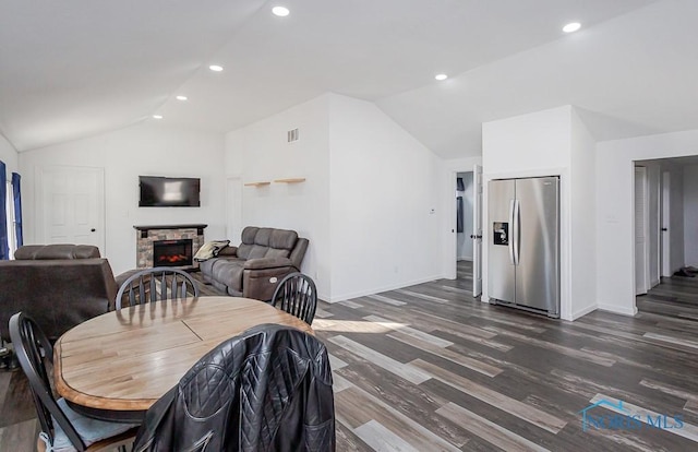 dining room with a fireplace, dark hardwood / wood-style floors, and vaulted ceiling