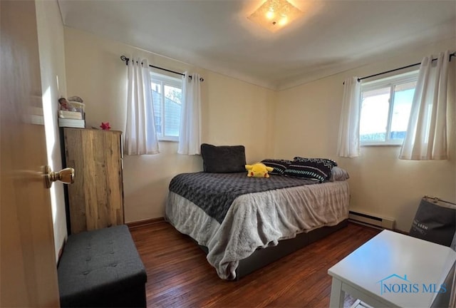 bedroom featuring baseboard heating, dark hardwood / wood-style flooring, and multiple windows