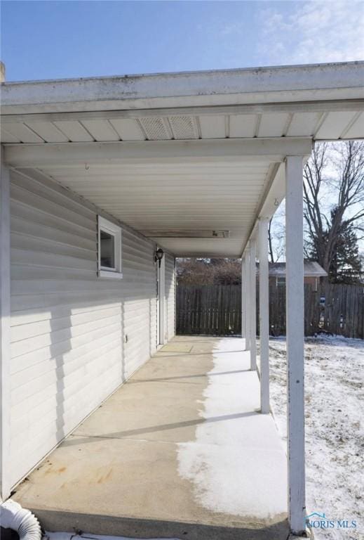 snow covered patio with a carport