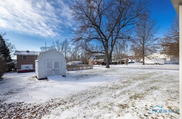 yard covered in snow featuring a storage unit