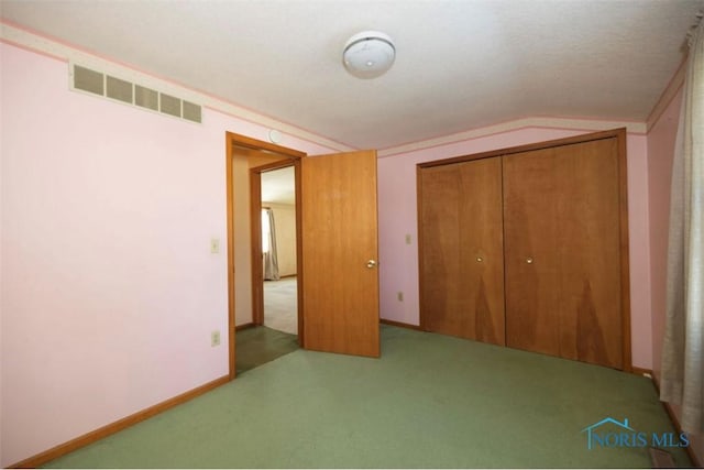 unfurnished bedroom featuring lofted ceiling, a closet, and carpet flooring