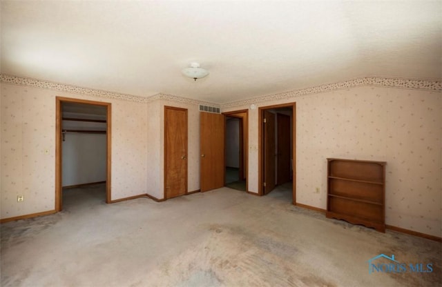 unfurnished bedroom with a walk in closet and light carpet