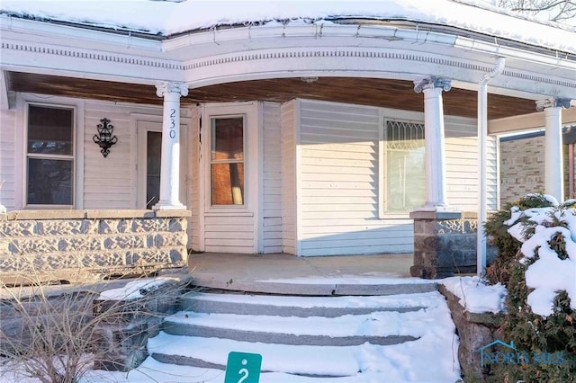 snow covered property entrance featuring a porch