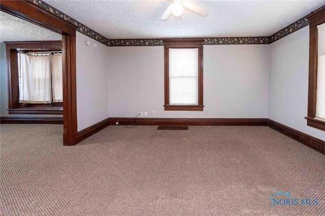 empty room featuring carpet floors, ceiling fan, and a textured ceiling