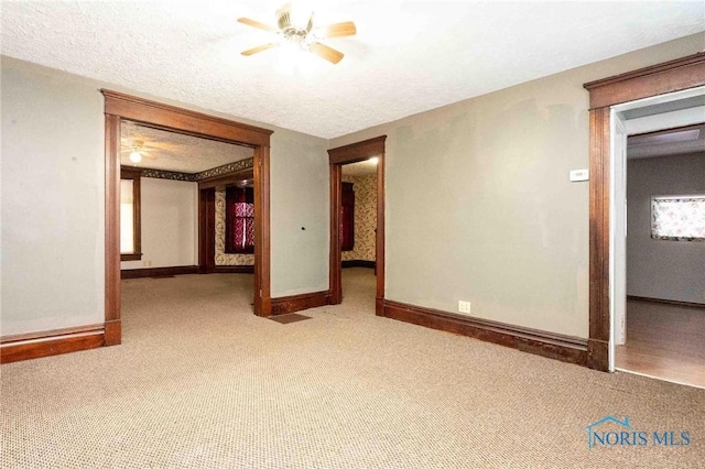 carpeted spare room featuring ceiling fan and a textured ceiling