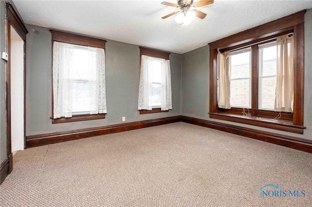 empty room featuring a textured ceiling, ceiling fan, and carpet flooring