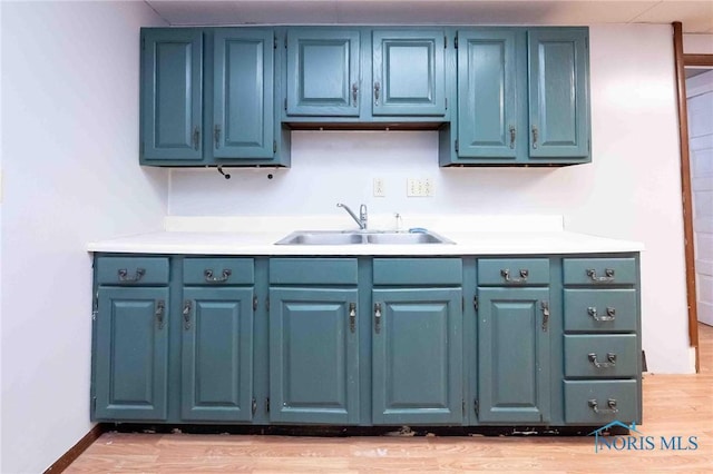 kitchen with sink, light hardwood / wood-style flooring, and blue cabinets