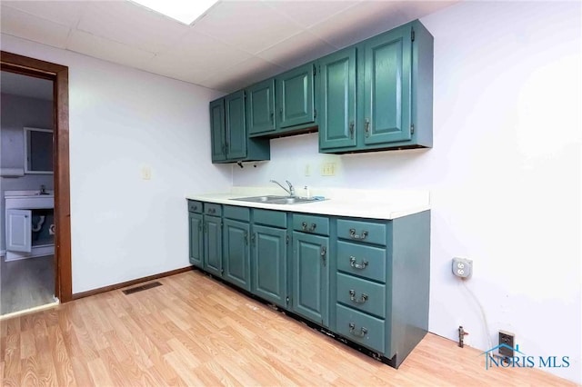 kitchen with a paneled ceiling, light wood-type flooring, and sink