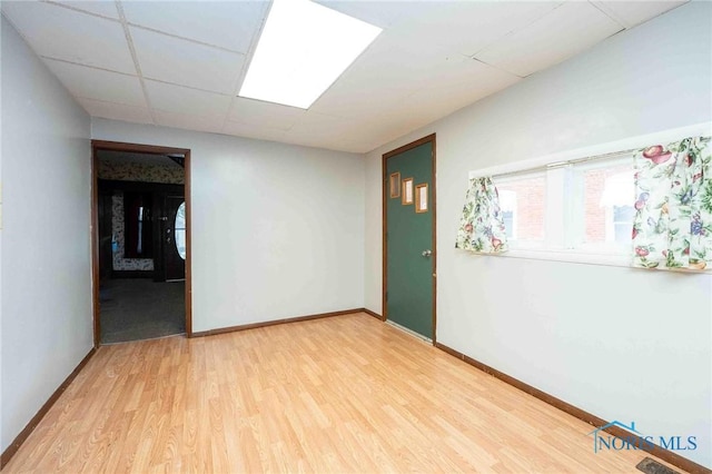 empty room with a paneled ceiling and wood-type flooring