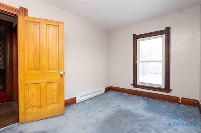 carpeted spare room with a baseboard heating unit