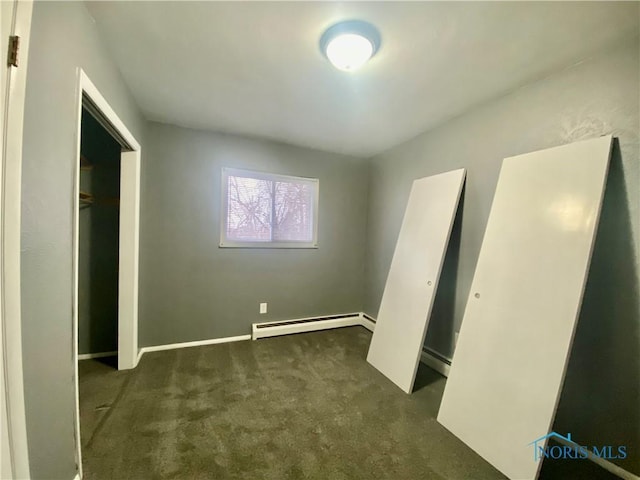 unfurnished bedroom with a baseboard heating unit, a closet, and dark carpet