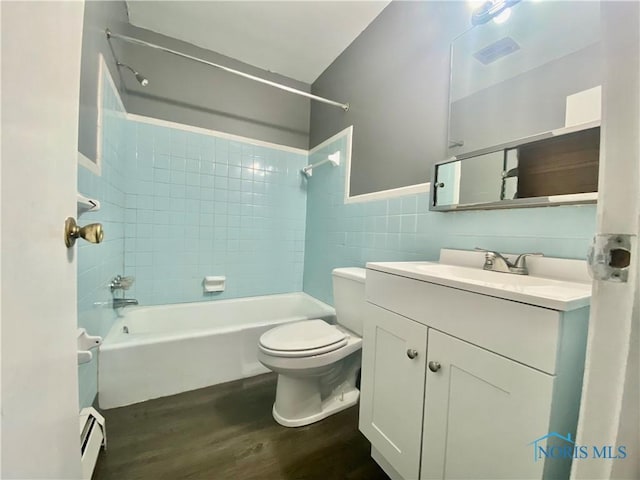 full bathroom with toilet, vanity, tile walls, a baseboard heating unit, and tiled shower / bath combo