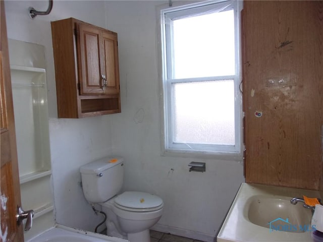 bathroom with toilet, a wealth of natural light, and sink