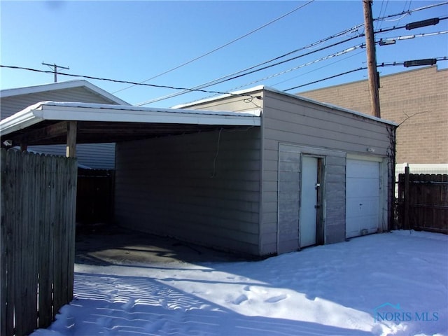 snow covered garage with a carport