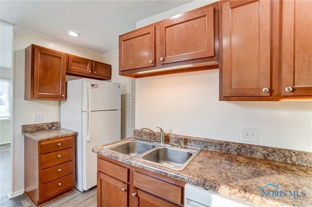 kitchen with light wood-type flooring, sink, and white appliances