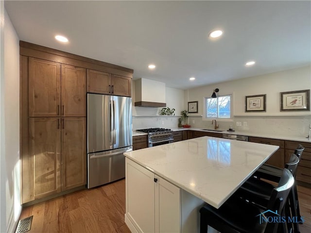 kitchen with premium range hood, a center island, appliances with stainless steel finishes, a kitchen breakfast bar, and light stone countertops