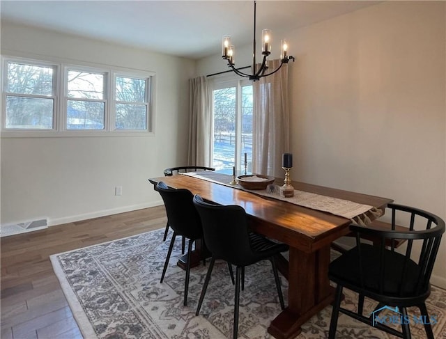 dining area with dark wood-type flooring and a chandelier