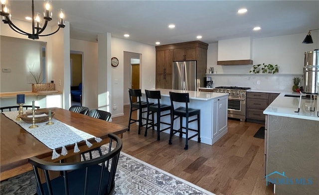 kitchen with dark hardwood / wood-style floors, a kitchen breakfast bar, custom exhaust hood, a center island, and stainless steel appliances