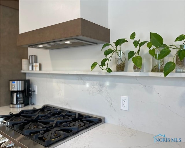 kitchen with tasteful backsplash, stovetop, and custom range hood