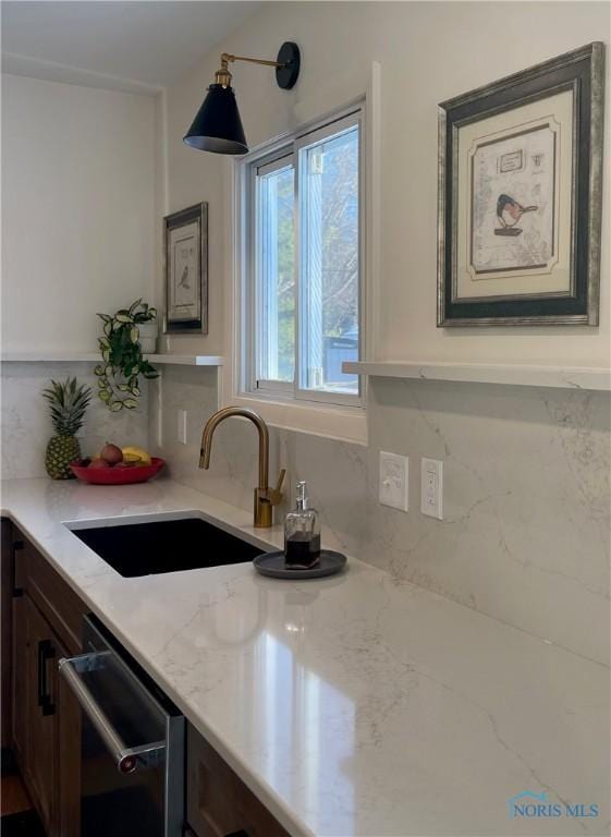 kitchen featuring light stone counters, sink, dark brown cabinetry, and dishwasher