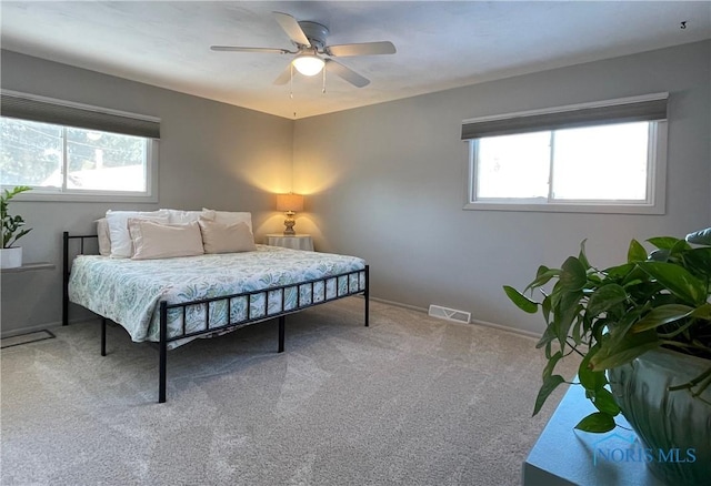 carpeted bedroom featuring multiple windows and ceiling fan