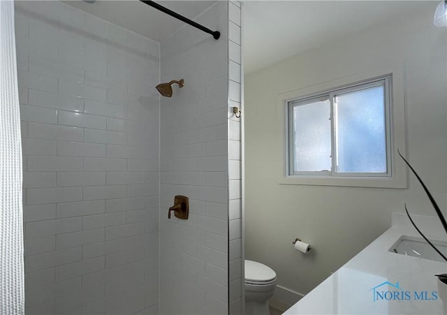 bathroom with vanity, a tile shower, and toilet