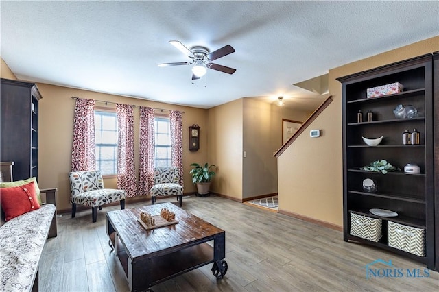 living room featuring hardwood / wood-style flooring, ceiling fan, and a textured ceiling