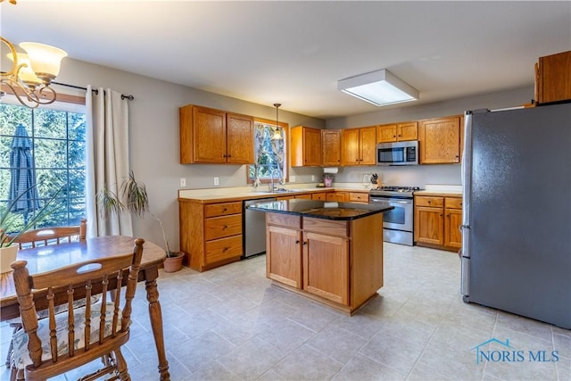 kitchen with sink, decorative light fixtures, a center island, appliances with stainless steel finishes, and a notable chandelier