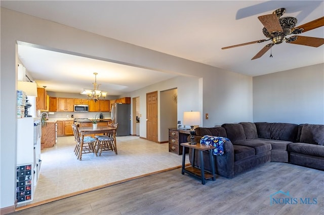 living room featuring ceiling fan with notable chandelier and light hardwood / wood-style floors