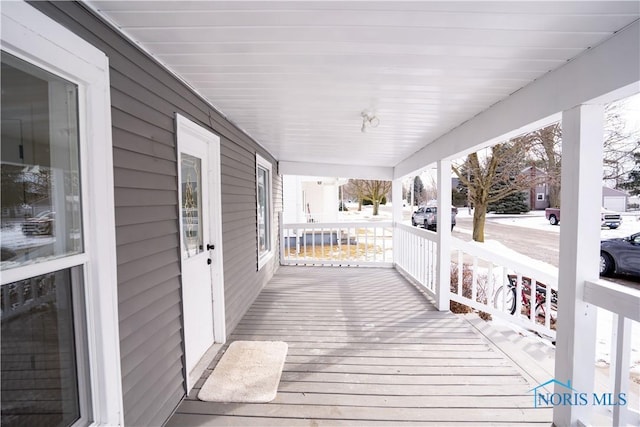 snow covered deck featuring covered porch