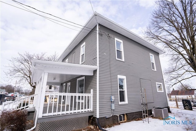 snow covered property featuring covered porch and central air condition unit