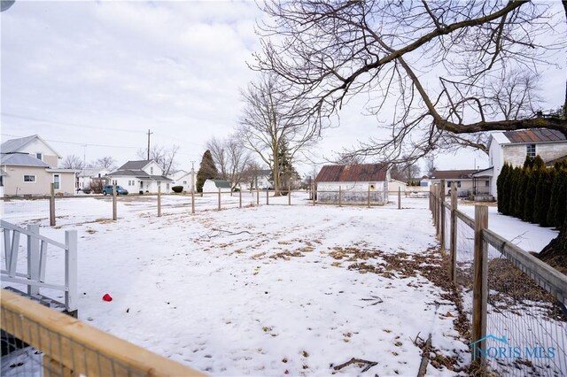 yard covered in snow featuring a residential view and fence