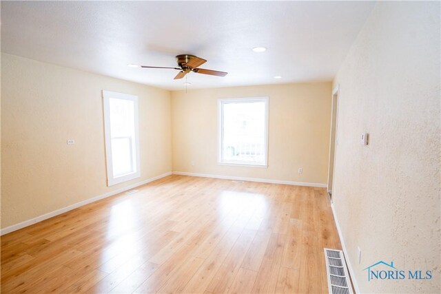 empty room featuring light wood-style floors, baseboards, visible vents, and ceiling fan