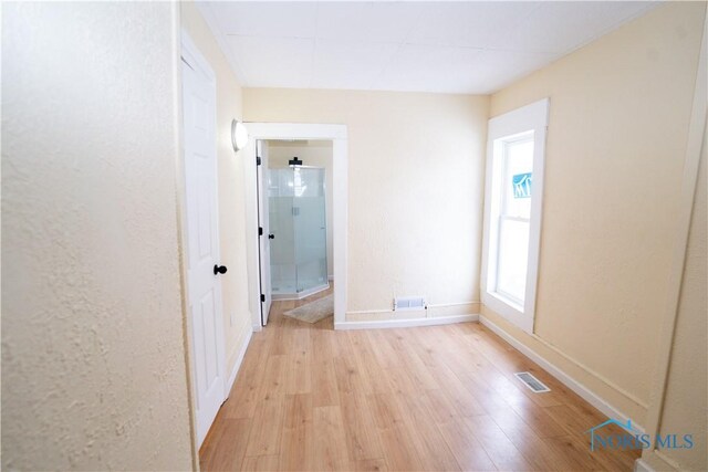 interior space featuring visible vents, light wood-style flooring, and baseboards