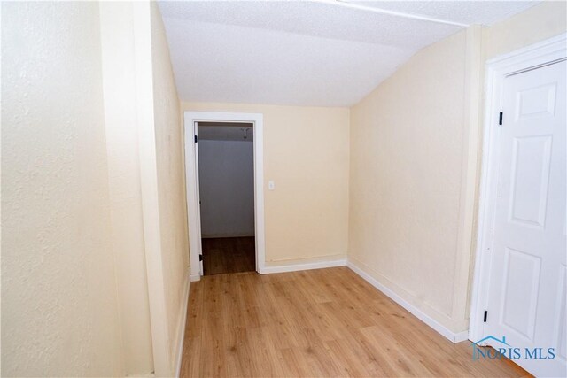 interior space with light wood-style floors, baseboards, and vaulted ceiling