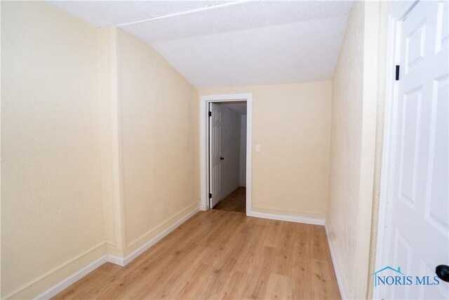 interior space with vaulted ceiling, baseboards, and light wood-style floors