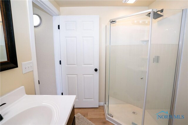 full bathroom featuring a stall shower, wood finished floors, and vanity