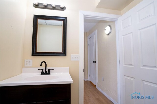 bathroom with baseboards, wood finished floors, and vanity