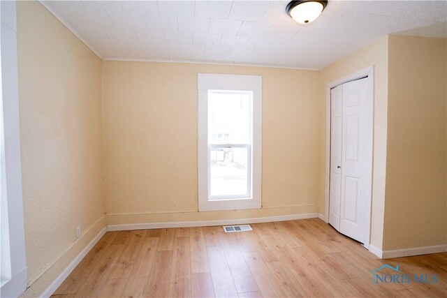 spare room with light wood-style flooring, visible vents, and baseboards